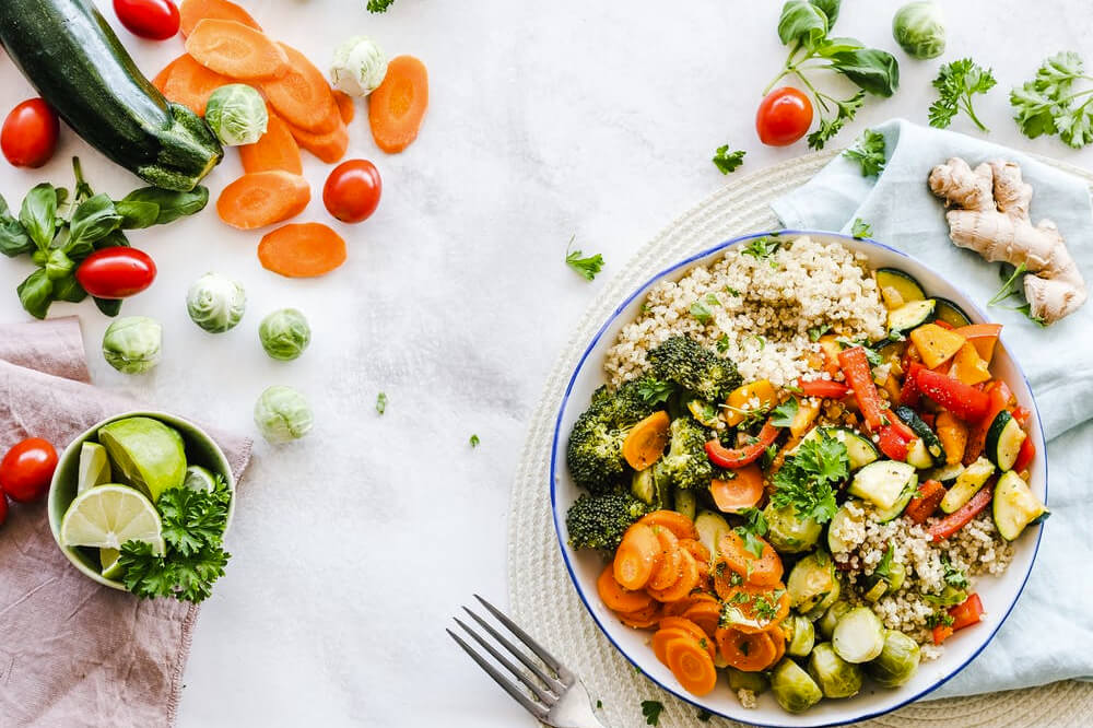A plate of veggies and rice with a fork and knife.