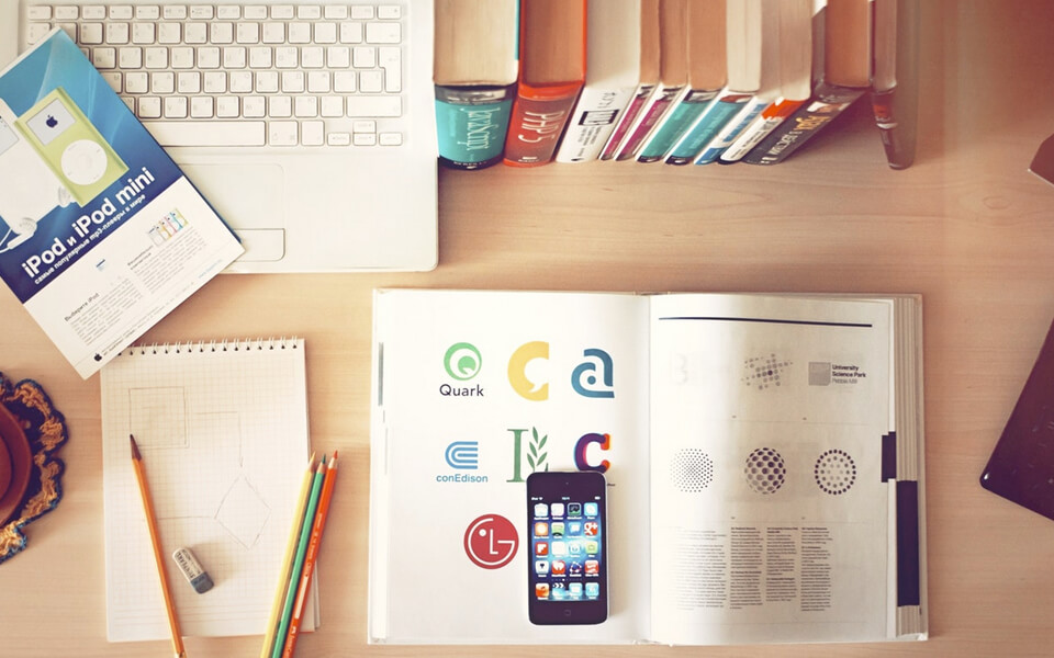  A well-organized desk with a laptop, books, and a cup of coffee, pencils and mobile phone, creating a productive and cozy workspace.
